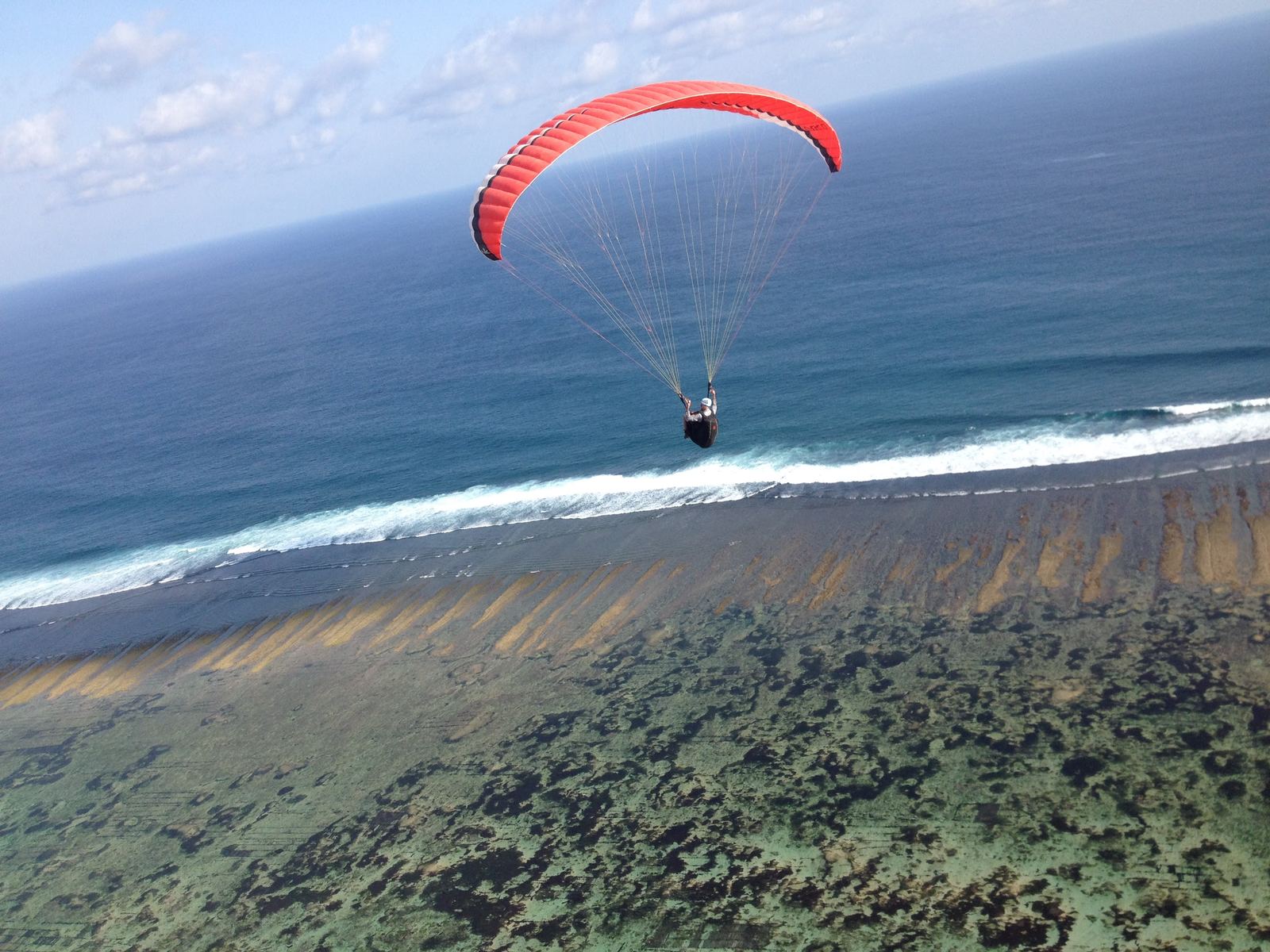 Parapente au-dessus d'une plage et d'un récif, à Bali.