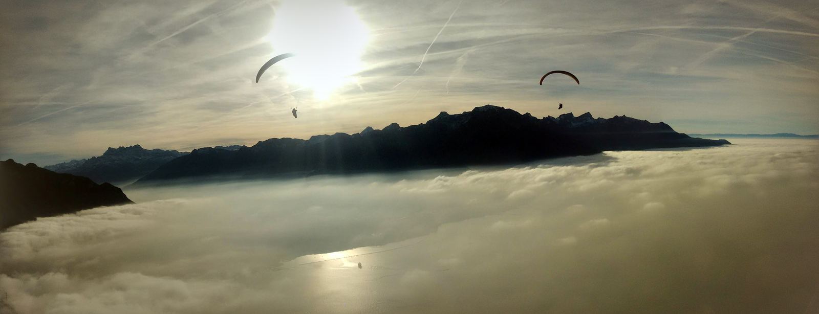 Deux parapentes au-dessus d'une mer de brouillard au coucher du soleil.