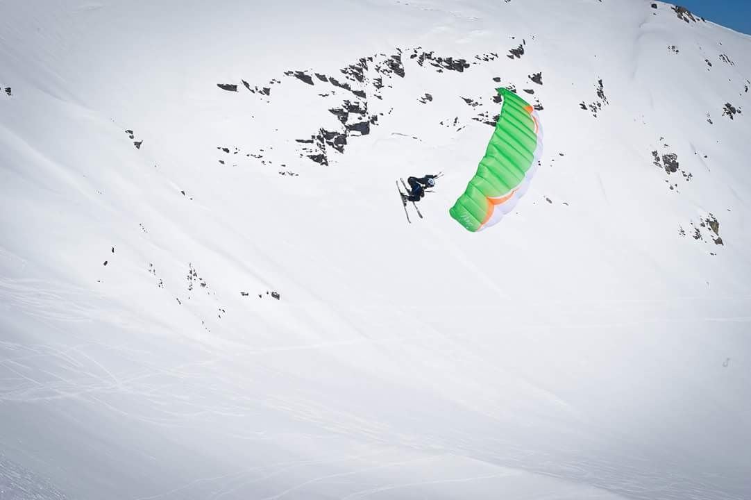 Une mini-voile verte au-dessus d'une pente enneigée.